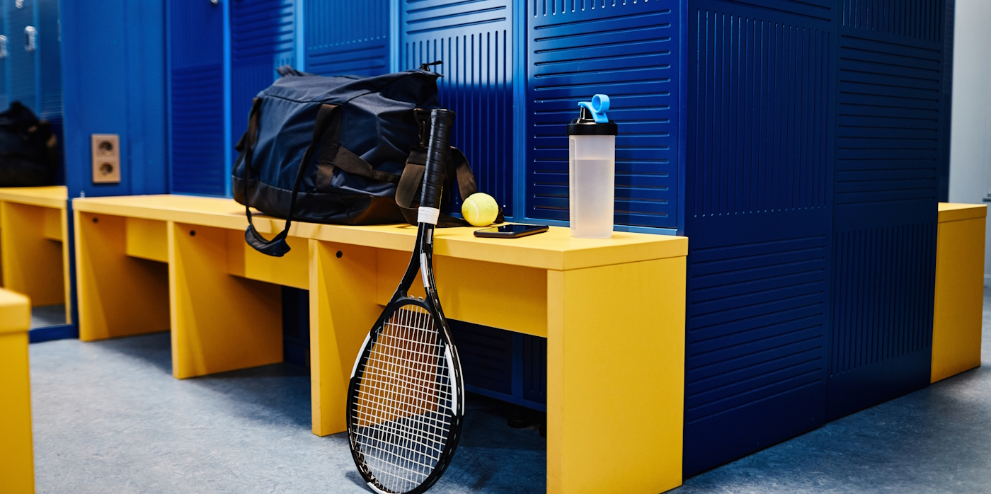 Background image of tennis racket and sports equipment in locker room in vibrant blue color, copy space